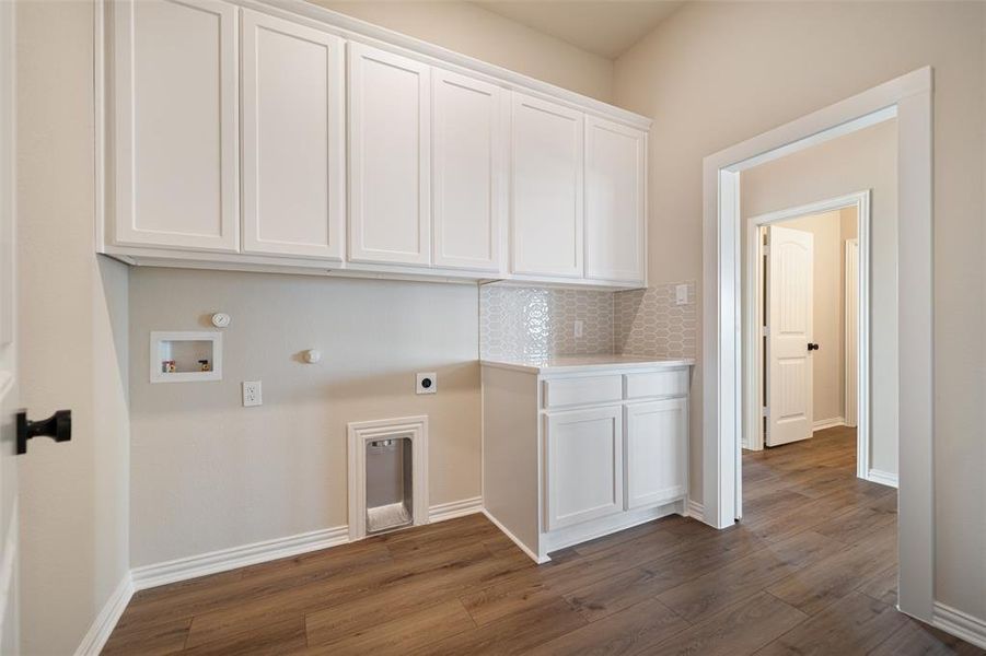Laundry area featuring cabinet space, hookup for an electric dryer, dark wood-style flooring, hookup for a washing machine, and hookup for a gas dryer