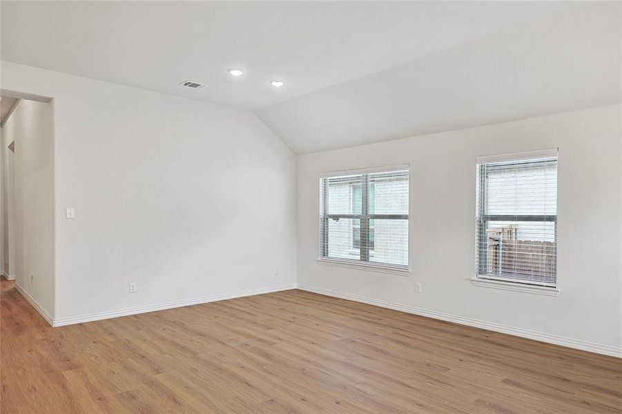 Empty room with lofted ceiling and light wood-type flooring