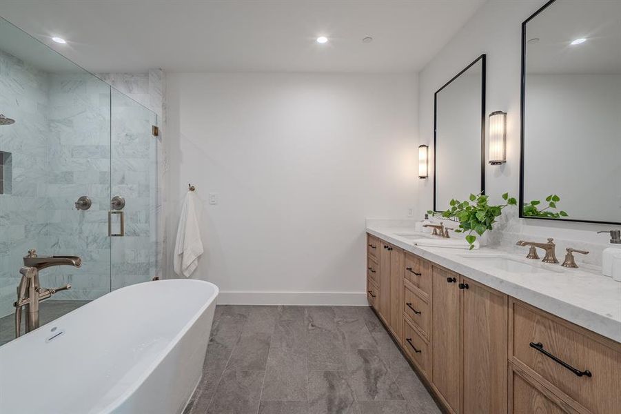 Bathroom with double vanity, a freestanding tub, a marble finish shower, and recessed lighting