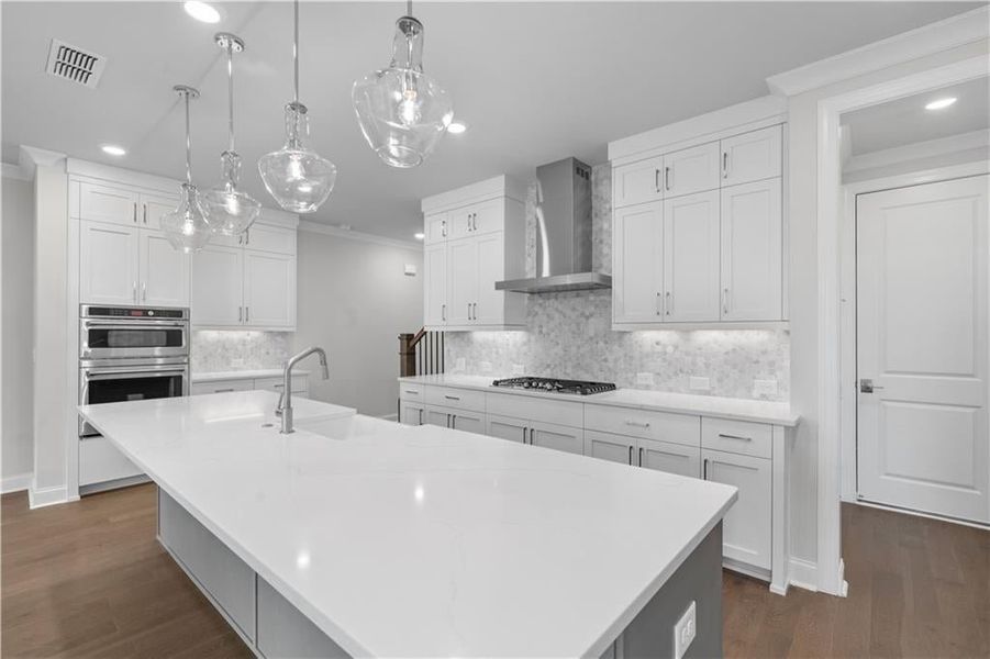 Kitchen featuring ornamental molding, white cabinetry, pendant lighting, recessed lighting, and dark wood-style flooring Kitchen featuring ornamental molding, white cabinetry, pendant lighting, recessed lighting, and dark wood-style flooring