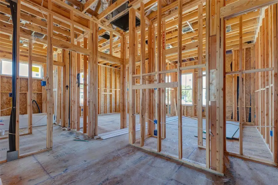Interior construction view showcasing the upper-level framing, defined room openings, exposed electrical rough-ins, and window placement. This perspective gives buyers a clear look at the home’s behind-the-walls progress, future bedroom and bath layout, and the careful structural planning taking shape before drywall and interior finishes are installed. Interior construction view showcasing the upper-level framing, defined room openings, exposed electrical rough-ins, and window placement. This perspective gives buyers a clear look at the home’s behind-the-walls progress, future bedroom and bath layout, and the careful structural planning taking shape before drywall and interior finishes are installed.