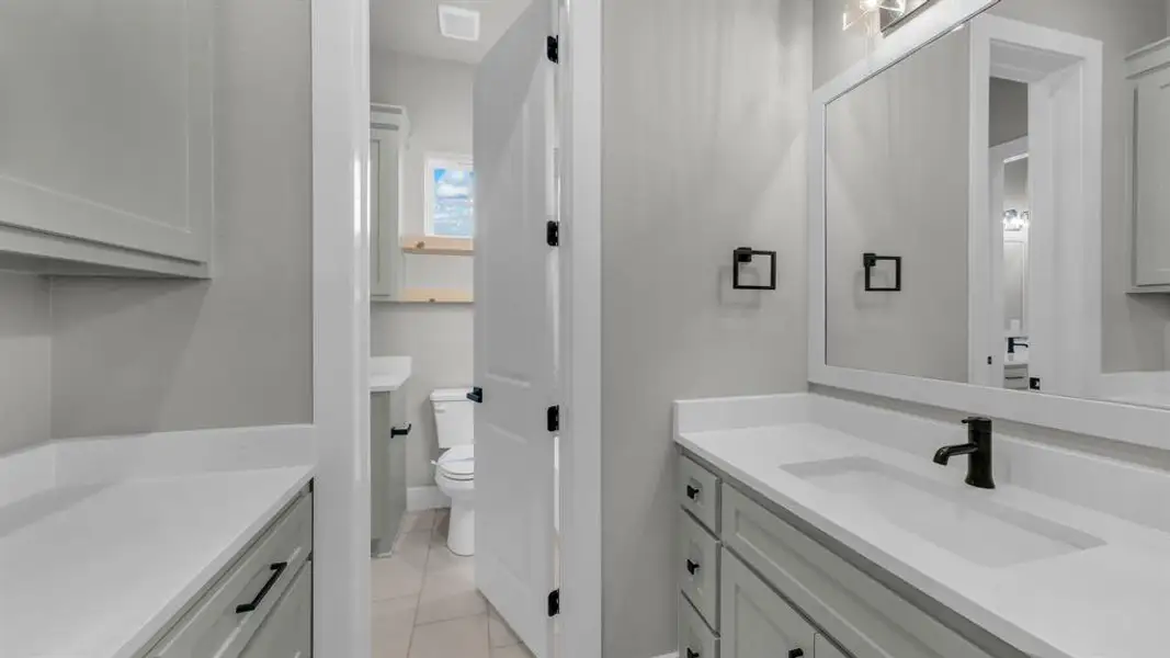 Bathroom featuring a white framed mirror, matte black faucet, and white countertop with an integrated sink Bathroom featuring a white framed mirror, matte black faucet, and white countertop with an integrated sink
