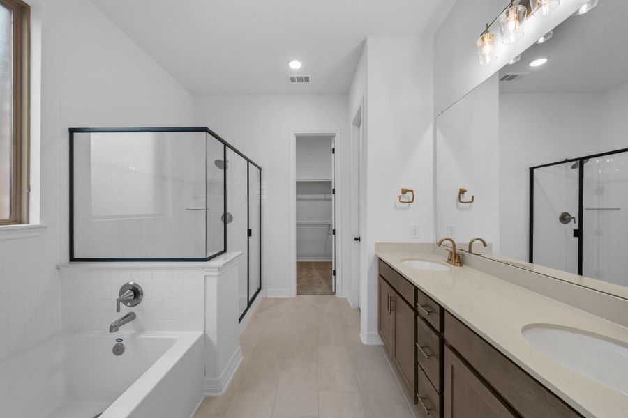 Serene and stylish primary bath featuring AW Laguna Collection with double vanity, warm stained cabinets with brass fixture, and light countertops for a relaxing retreat.