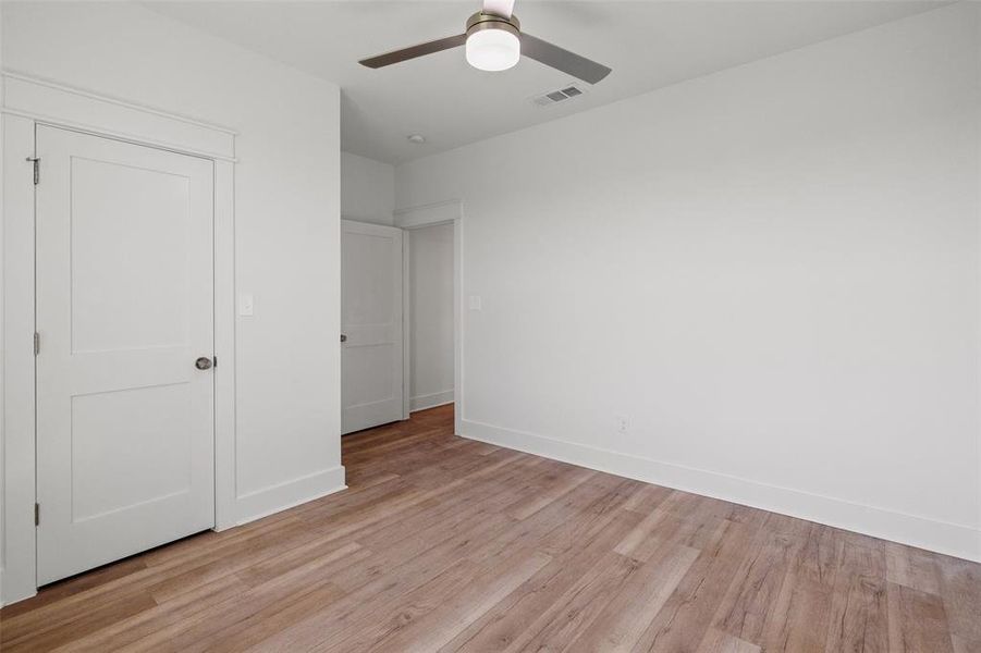 Room featuring wood-finish flooring, crisp white walls, white baseboards, and a contemporary ceiling fan