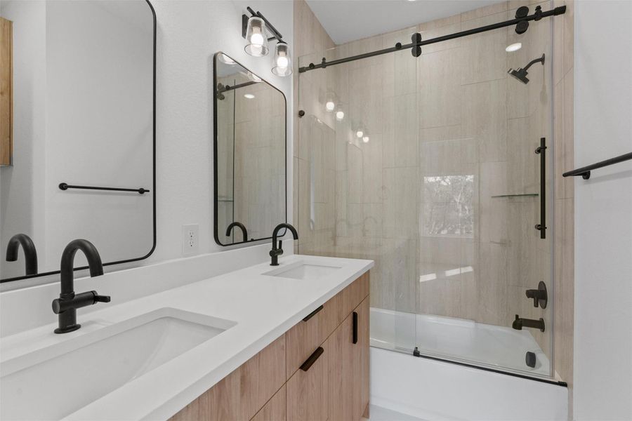 A well-appointed bathroom features a double vanity with ample counter space and a modern shower-tub combination. A well-appointed bathroom features a double vanity with ample counter space and a modern shower-tub combination.