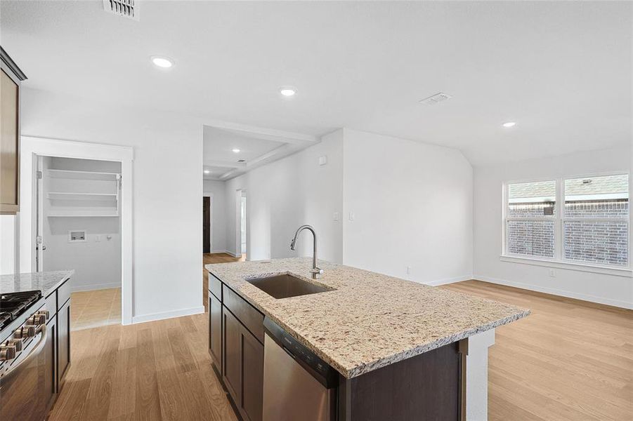 Kitchen featuring light stone countertops, a center island with sink, light hardwood / wood-style floors, stainless steel appliances, and sink