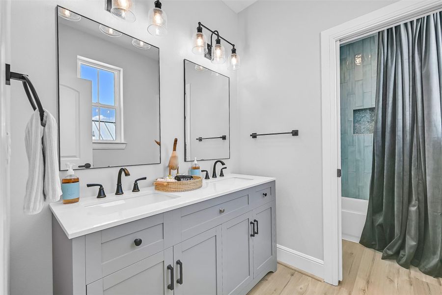 This bunk room ensuite includes dual vanities, oversized mirrors, and generous counter space create a primary bath that feels polished, functional, and ready for everyday luxury.  Theres also a nice tub to bathe the kiddos after a long day at the beach!