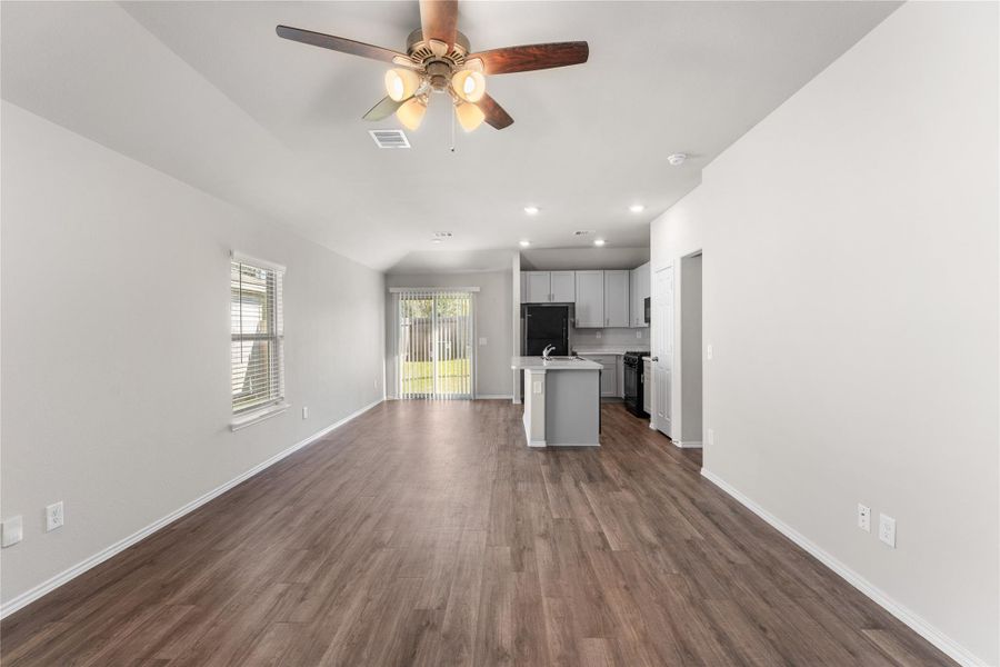 View of living area with ceiling fan and direct access to kitchen and backyard. View of living area with ceiling fan and direct access to kitchen and backyard.