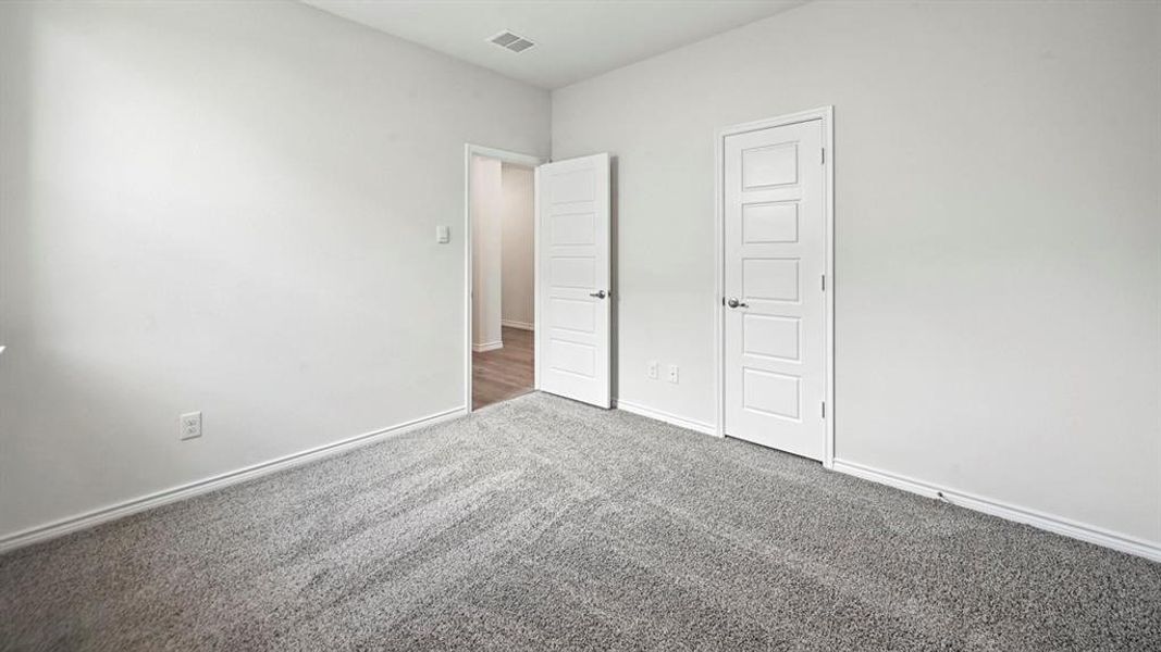 Carpeted room with a five-panel interior door, white baseboards, and light-colored walls