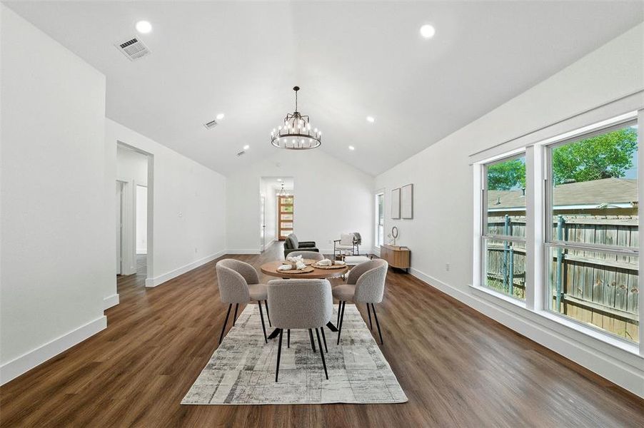 Dining space featuring a chandelier, dark wood finished floors, vaulted ceiling, and recessed lighting