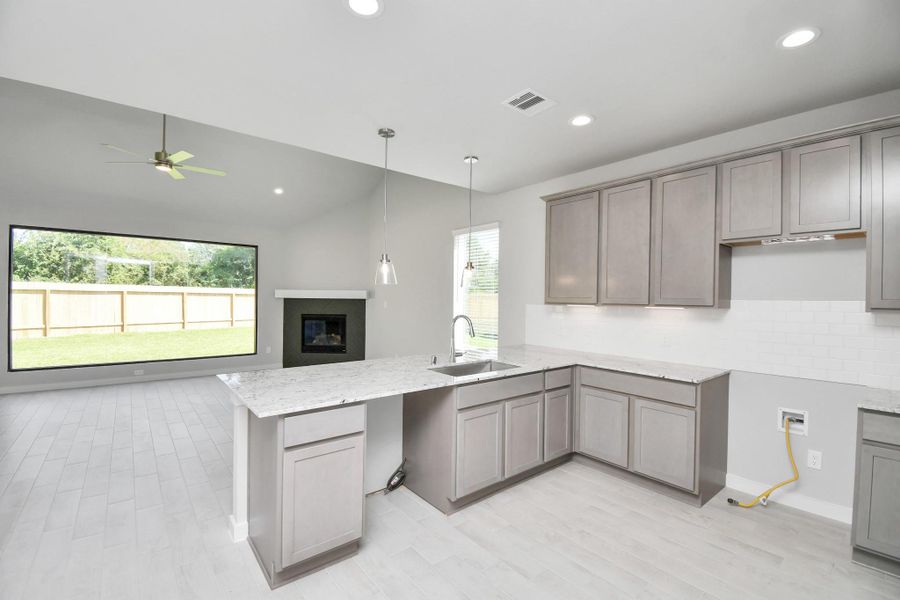 The kitchen is a culinary haven, featuring granite countertops, a tile backsplash, stainless steel appliances, 42” upper cabinets, and undercabinet lighting. Sample photo of completed home with similar floor plan. Actual colors and selections may vary.