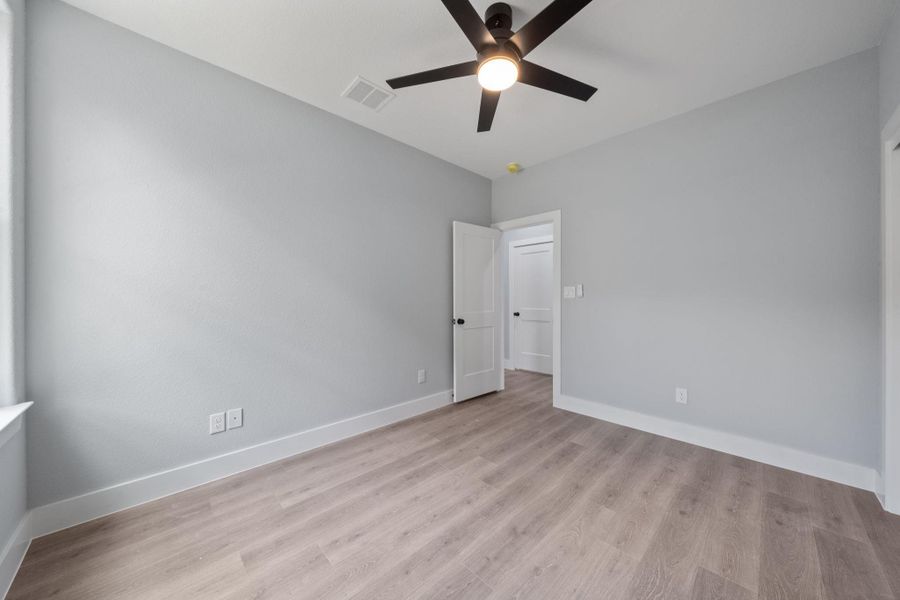 Spacious room featuring light wood-finish flooring, light gray walls, and white trim