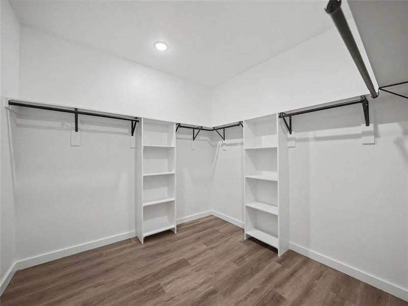 Spacious closet featuring wood-finish flooring, recessed lighting, and white built-in shelving units Spacious closet featuring wood-finish flooring, recessed lighting, and white built-in shelving units