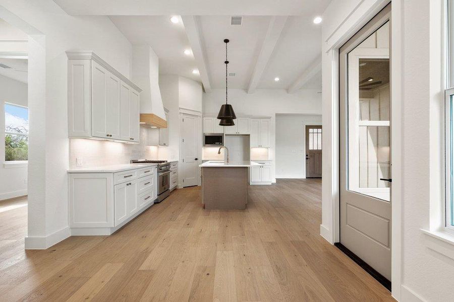 The kitchen features white cabinetry, a central island, and wood flooring