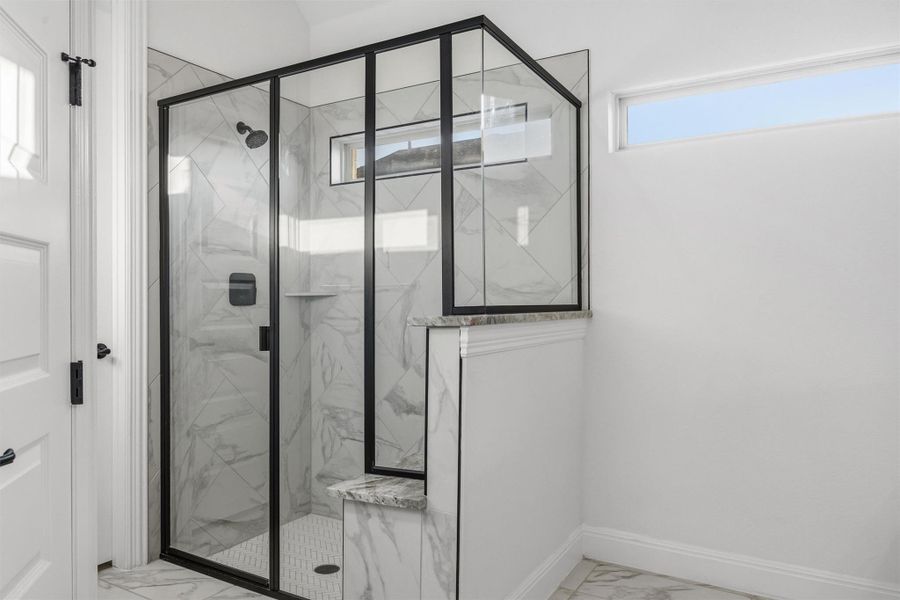 Bathroom featuring light marble finish floors and a marble finish shower
