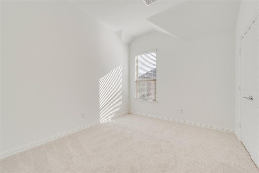 Empty room featuring vaulted ceiling and light colored carpet