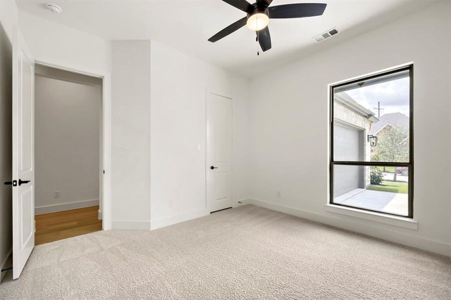 Bright room featuring light-toned carpet flooring, white walls, and a ceiling fan with integrated lighting Bright room featuring light-toned carpet flooring, white walls, and a ceiling fan with integrated lighting