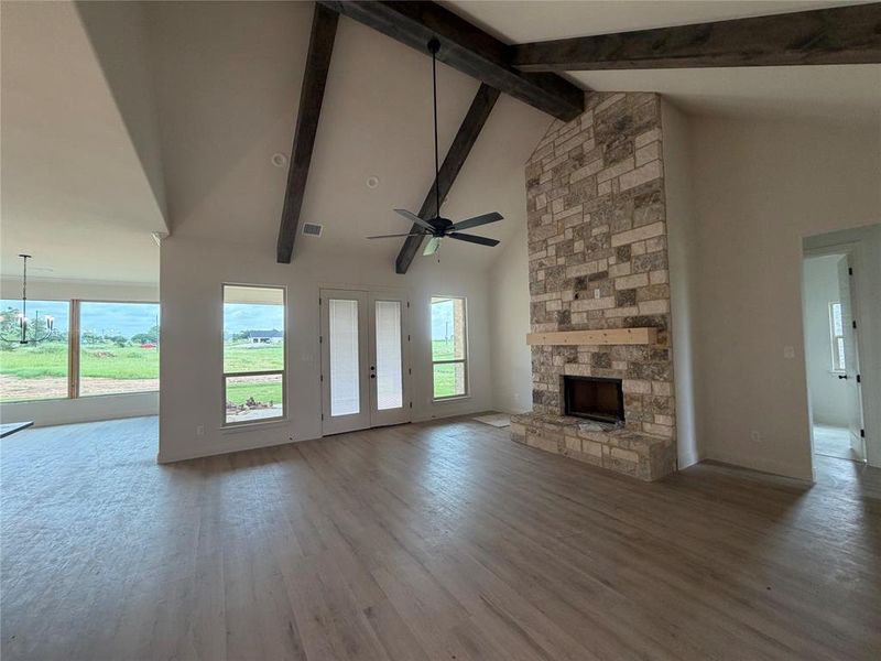 Large living with cathedral ceiling, stained beams and double back patio door