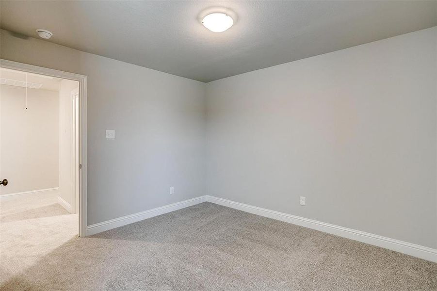 Carpeted empty room featuring attic access and baseboards