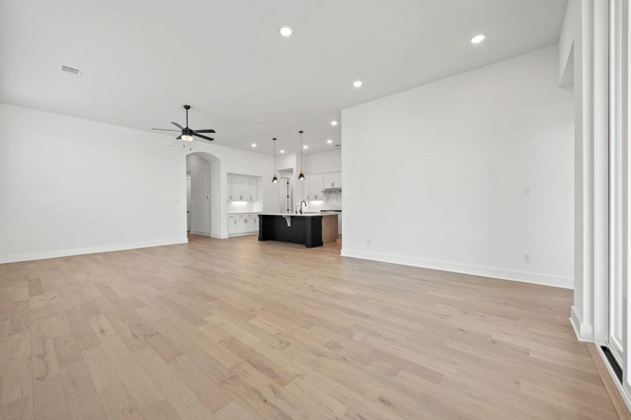 Unfurnished living room featuring recessed lighting, arched walkways, light wood-style floors, and a ceiling fan