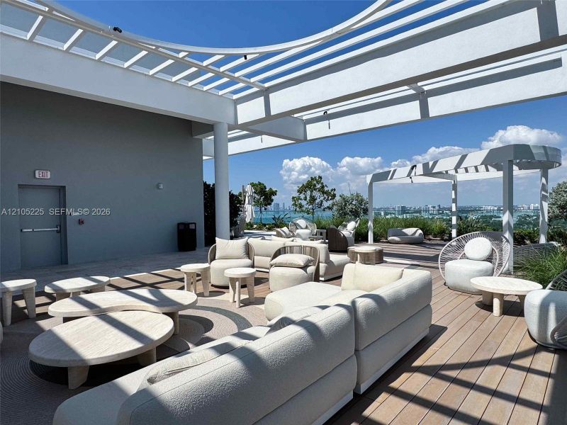 Expansive rooftop deck featuring a louvered pergola, wood-finish flooring, and a panoramic skyline backdrop