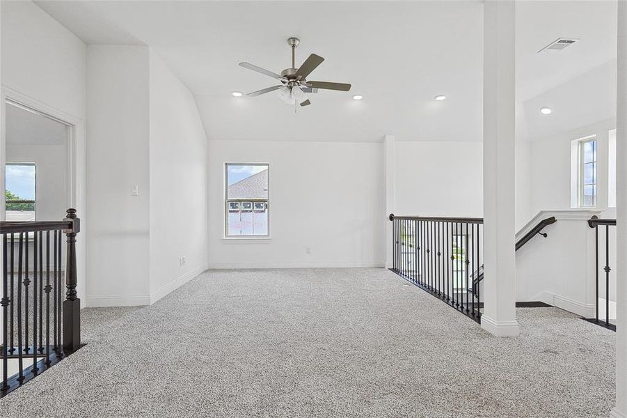 Unfurnished living room featuring ceiling fan, light carpet, and lofted ceiling