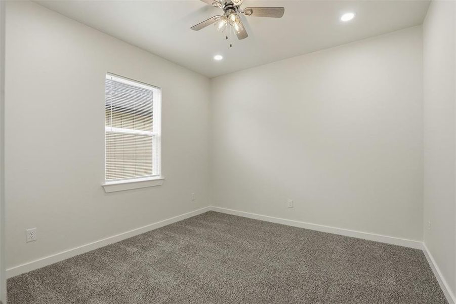 Carpeted interior space featuring a window with blinds, a ceiling fan with integrated lighting, and recessed ceiling lights
