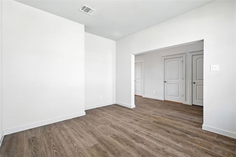 Kitchen with white cabinetry, tasteful backsplash, light stone countertops, an island with sink, and dark wood-style flooring Kitchen with white cabinetry, tasteful backsplash, light stone countertops, an island with sink, and dark wood-style flooring