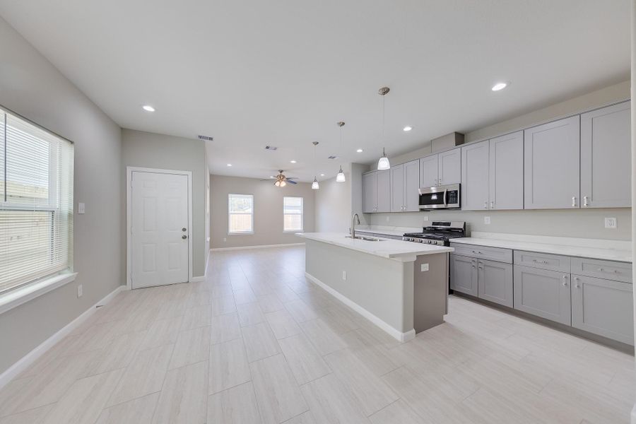 Sleek light gray cabinetry and modern finishes deliver a sophisticated, high-end kitchen aesthetic perfect for your first home’s culinary adventures