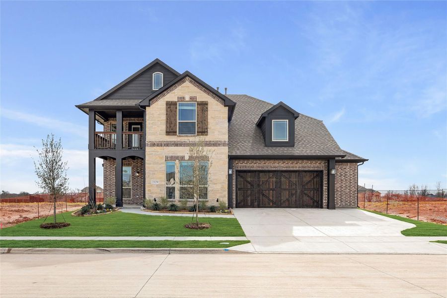 Two-story brick and stone home with two-car garage, upper balcony, and wood shutters on a corner lot Two-story brick and stone home with two-car garage, upper balcony, and wood shutters on a corner lot