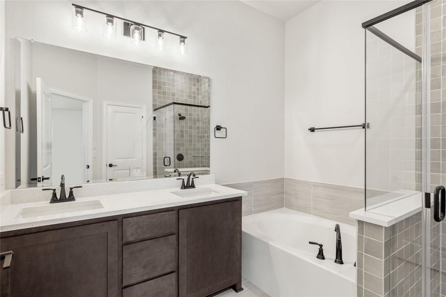 Bathroom with double-sink vanity, soaking tub, and glass-enclosed tile shower with dark fixtures Bathroom with double-sink vanity, soaking tub, and glass-enclosed tile shower with dark fixtures