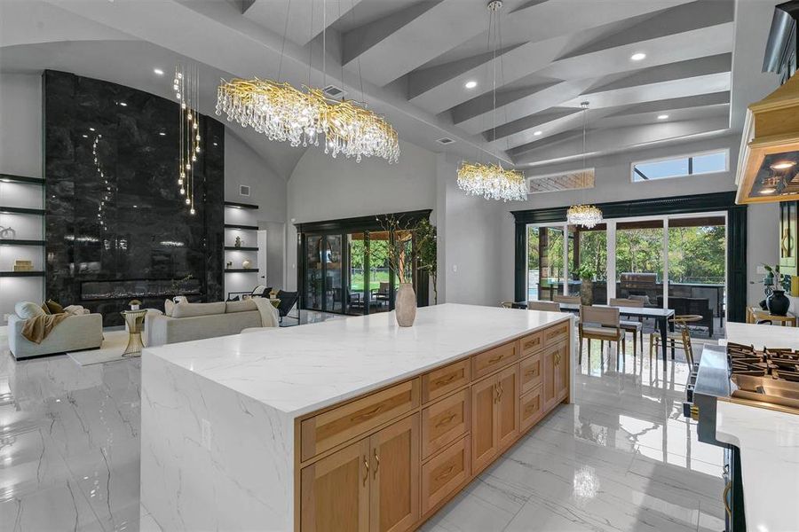 Kitchen with pendant lighting, plenty of natural light, light stone counters, and a large island