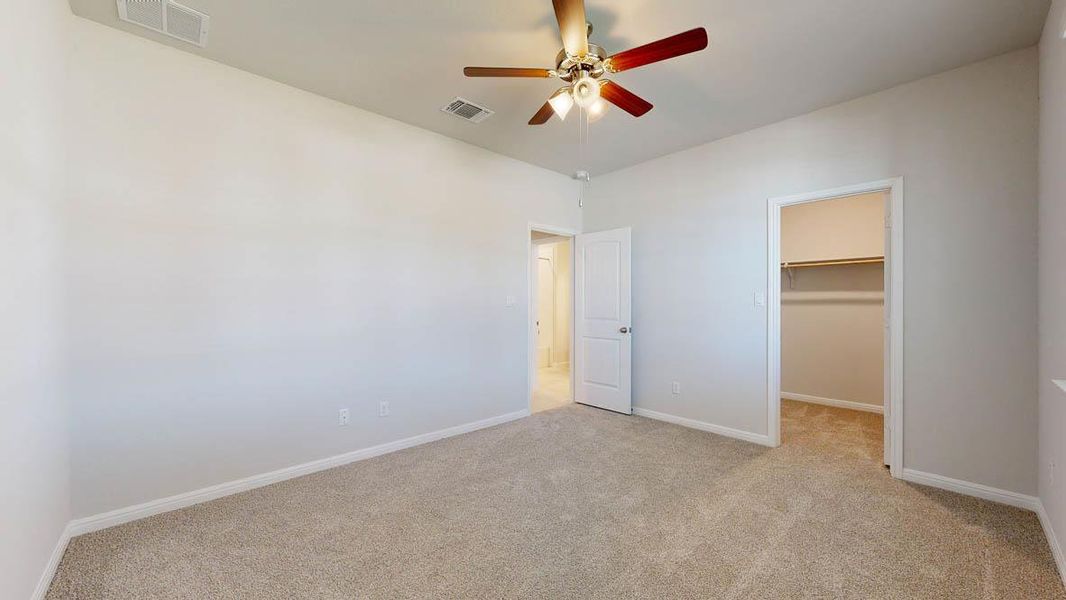Unfurnished bedroom with light colored carpet, a spacious closet, and ceiling fan