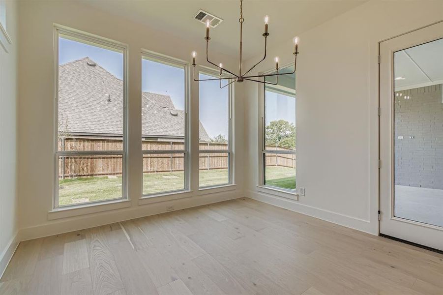 Unfurnished dining area with light wood-type flooring, healthy amount of natural light, and a chandelier Unfurnished dining area with light wood-type flooring, healthy amount of natural light, and a chandelier