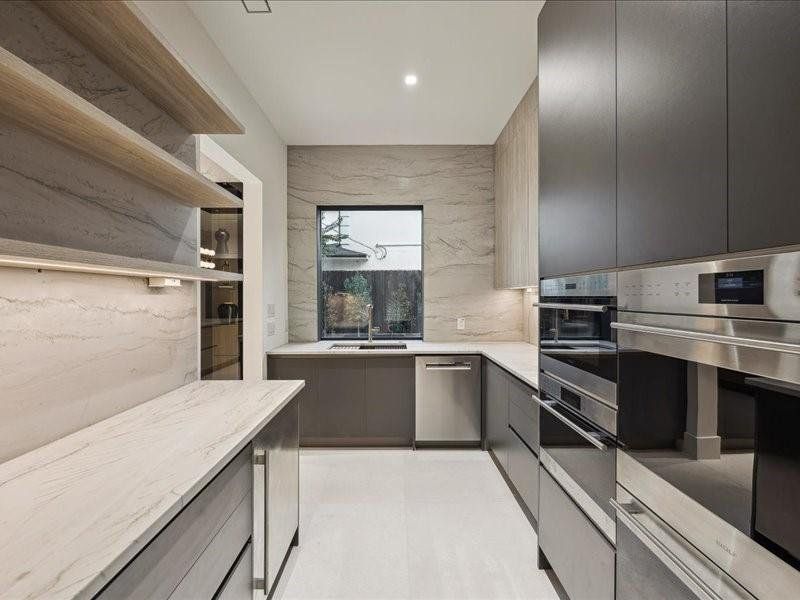 Another view of the prep kitchen reveals a second sink and a large window that fills the space with natural light. Granite countertops extend to the ceiling, creating a bright and seamless design.