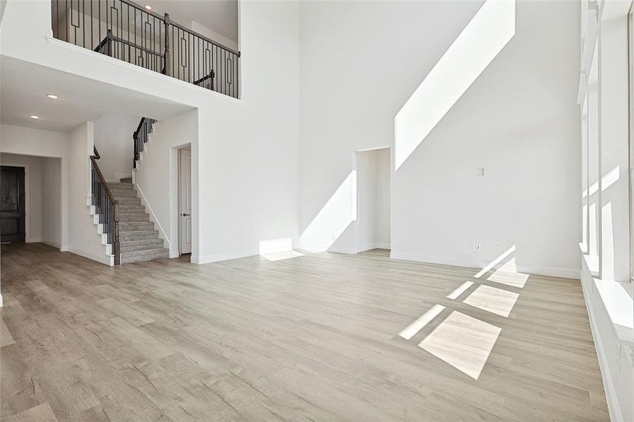 Unfurnished living room with light hardwood / wood-style floors and a high ceiling