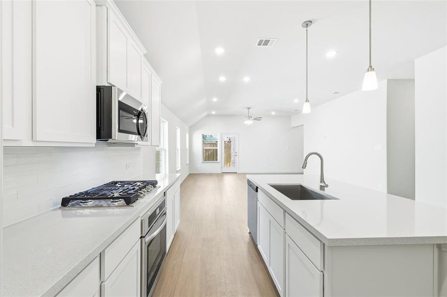 Kitchen featuring white cabinets, hanging light fixtures, light wood-style floors, a kitchen island with sink, and recessed lighting