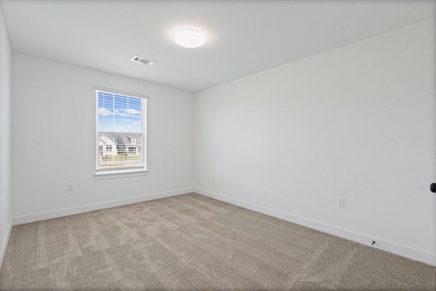 Neutral-toned carpeting, white walls, and a single window with blinds Neutral-toned carpeting, white walls, and a single window with blinds