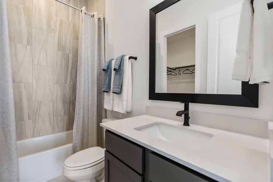 Neutral tile surround, tub/shower combination, and a bright, functional layout ideal for guests