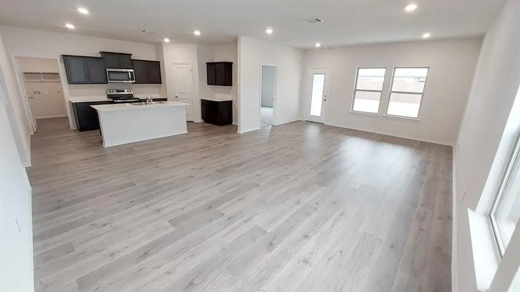 Kitchen featuring open floor plan, an island with sink, dark cabinets, recessed lighting, and light wood-type flooring Kitchen featuring open floor plan, an island with sink, dark cabinets, recessed lighting, and light wood-type flooring