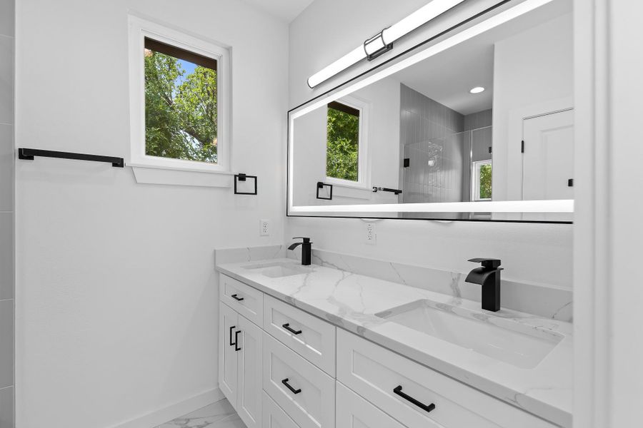 Dual vanity with pristine white marble-patterned countertops and sleek black fixtures.