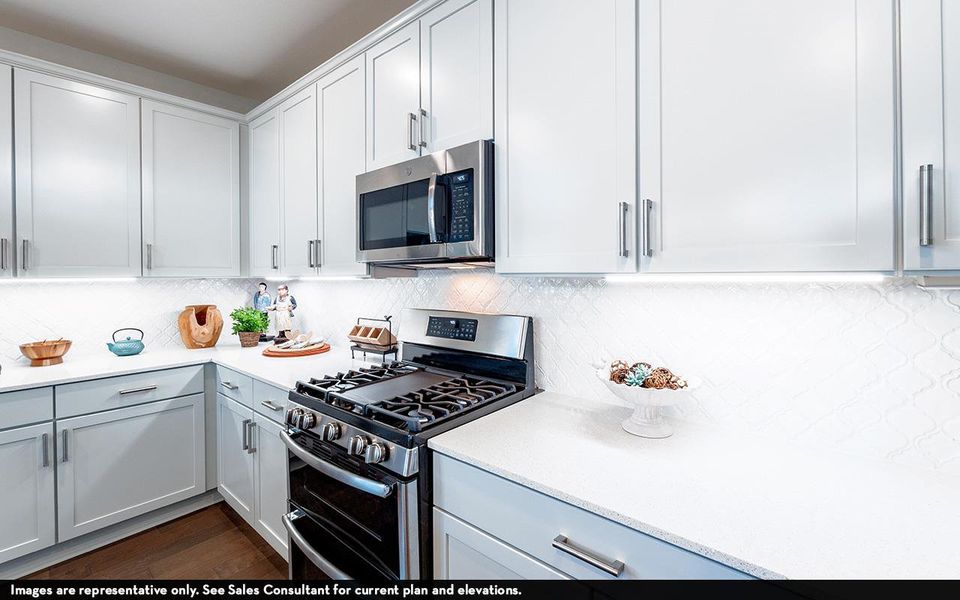 Kitchen featuring appliances with stainless steel finishes, light countertops, tasteful backsplash, dark wood-type flooring, and white cabinets Kitchen featuring appliances with stainless steel finishes, light countertops, tasteful backsplash, dark wood-type flooring, and white cabinets