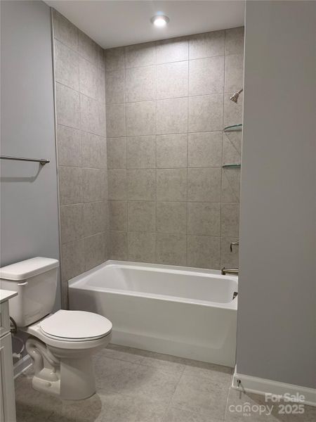 Loft bathroom has tile floors and tub surround