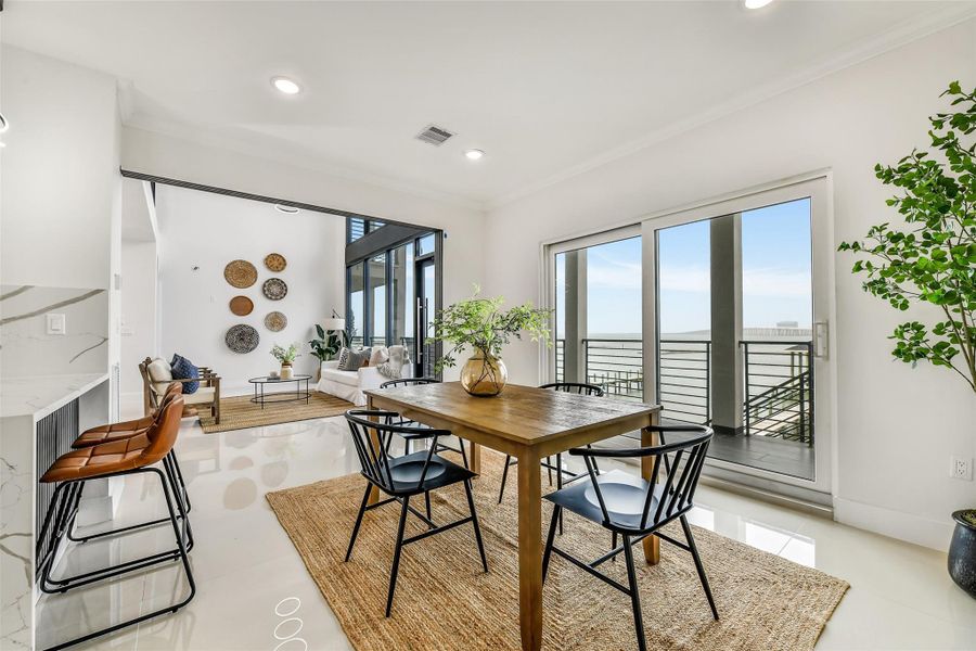 Sunlight floods this expansive living and dining space, creating an atmosphere that feels open, refined, and effortlessly elegant. Every gathering here feels elevated, with the bay always just beyond your view.