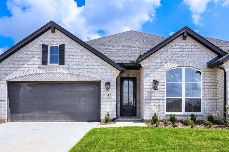 White brick exterior featuring a dark gray garage door, arched entry window, dark wood front door, and black exterior lighting fixtures