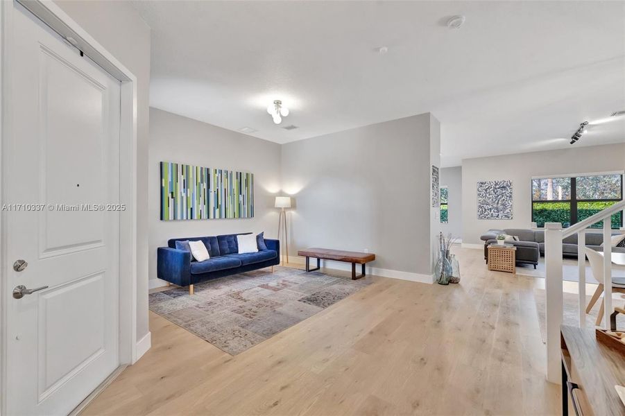 Enter home and step into foyer. On the left is a living room, stairs to the right, and garage and powder room behind this photographer