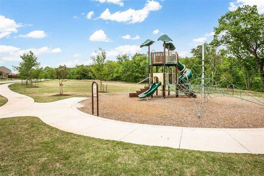 Community playground featuring a multi-level play structure with slides and climbing elements, set on wood chip surfacing
