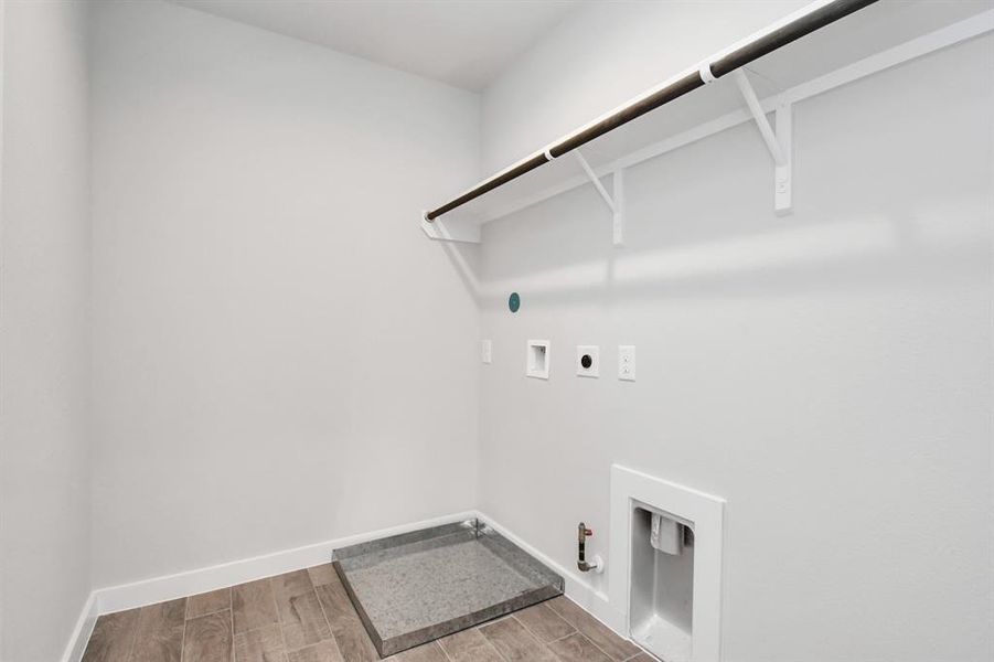 A stylish laundry room where practicality meets a contemporary aesthetic. The dark finishes lend a sophisticated touch, creating a space that is both functional and visually appealing. Both electric and gas connections available. Sample photo of completed home with same plan. Actual colors and selections may vary.