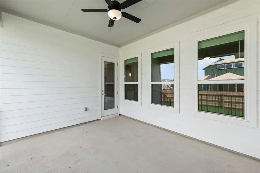An inviting covered patio features a ceiling fan, offering a cool retreat for outdoor leisure.