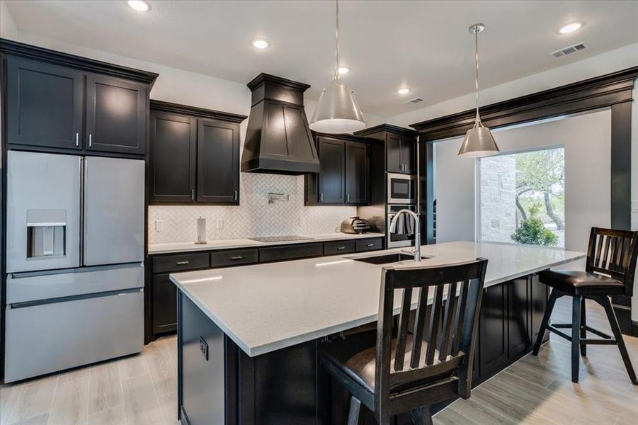 Kitchen featuring dark cabinets, stainless steel appliances, and a breakfast bar area